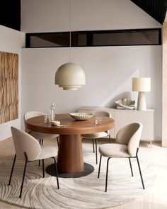 a round wooden table with four chairs around it in a room that has an area rug on the floor