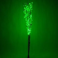 a green lighted tree in the middle of a dark room with no leaves on it