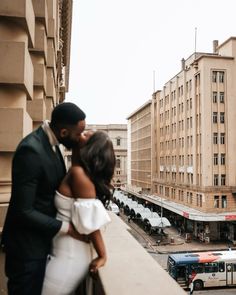 a man and woman standing next to each other in front of a cityscape