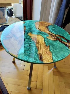 a glass table with wood and metal legs on the floor in front of a window