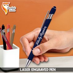 a person holding a pen in their left hand and writing on it with the words laser engraved pen