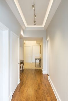 an empty room with hard wood floors and white walls, along with a bench in the middle