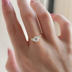 a woman's hand with a diamond ring on top of her finger and the other hand holding it