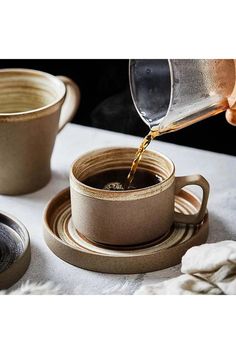 someone pouring coffee into a cup on a table