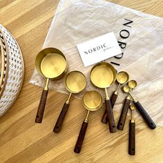 six brass spoons sitting on top of a wooden table