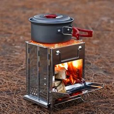 an outdoor stove with a pot on top and fire in the oven next to it