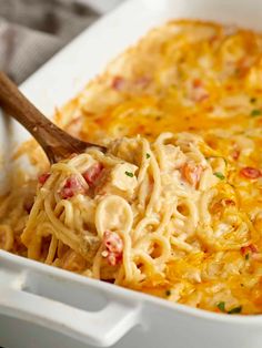 a casserole dish with noodles and meat in it, being scooped from the casserole