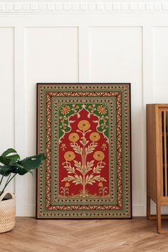 a red and green rug sitting on top of a wooden floor next to a potted plant