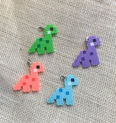 four different colored pixel keychains sitting on top of a piece of cloth