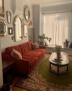 a living room with red couches and mirrors on the wall above it's coffee table