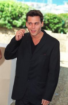 a man in a black suit is posing for the camera