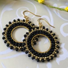 Stunningly beautiful seed bead hoop earrings made with black 8/0 and gold metallic 11.0 seed beads. The french hook earwires and findings are are 14kt gold plated. These very lightweight earrings are handmade by me with each tiny bead individually woven. They measure 2 inches total including the earwires. The hoops are 1.5 inches. These earrings go perfectly with all outfits and occasions. Wear these stunning earrings and get ready for compliments Thanks for looking and please stop by again. Seed Bead Hoop Earrings, Bead Hoop Earrings, Hoop Earrings Handmade, Small Hoop Earrings, Lightweight Earrings, Beaded Hoop Earrings, Beaded Hoops, Beaded Dangle Earrings, Earrings Black