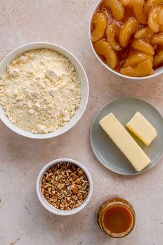 ingredients for apple pie laid out in bowls on a white counter top, including apples, butter, and pecans