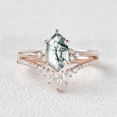 an engagement ring with a green and white stone surrounded by diamonds on a white background