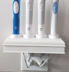 three electric toothbrushes sitting on top of a shelf