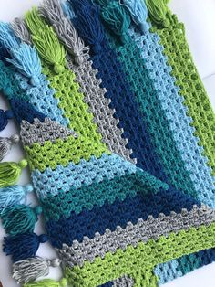 a crocheted blanket with tassels on it