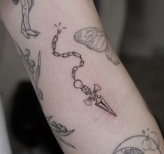 a woman's arm with tattoos on it and a chain attached to the wrist