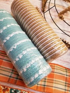 two rolls of fabric sitting next to each other on top of a wooden tablecloth