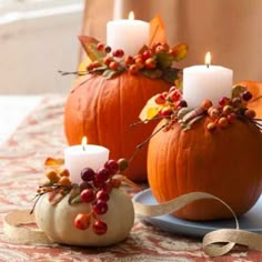 two pumpkins decorated with candles on a table