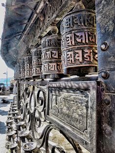 there are many metal bells on the side of this building that is very old and rusty