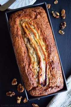 a loaf of bread sitting on top of a black table next to nuts and a knife