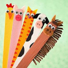 five different colored toothbrushes with faces and noses on them, each holding a wooden stick