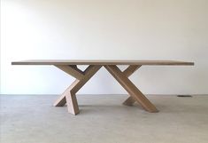 a wooden table sitting on top of a cement floor next to a white wall in an empty room