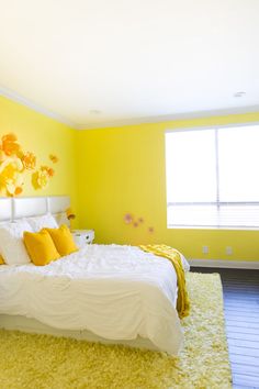 a bedroom with yellow walls and white bedding in the center, along with a rug on the floor