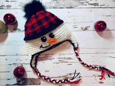 a crocheted snowman hat with a black and red pom - pom