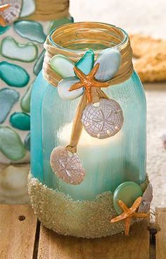 a glass jar filled with sand and starfish sitting on top of a wooden table