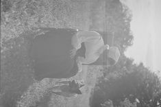 a woman laying in the grass with her back turned to the camera, looking down