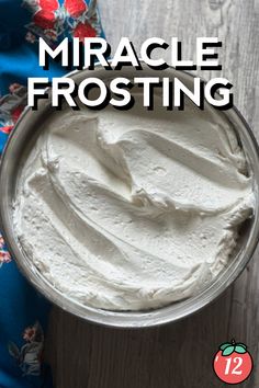 a bowl filled with white frosting on top of a wooden table