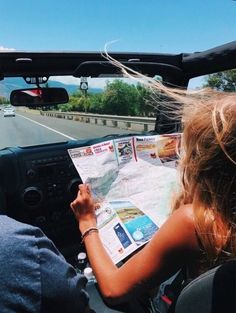 a woman sitting in the drivers seat of a car looking at a map