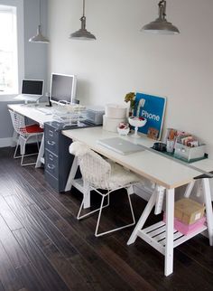 an office with two desks and three computers on it's sides, in front of a window