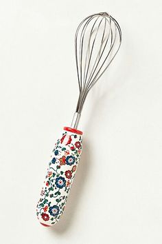 the whisk is decorated with colorful flowers and has a red handle on it