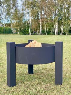 a large metal fire pit sitting on top of a lush green field