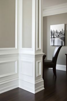 White interior architectural details with a black and white cityscape painting on the wall in the background. Elegant Trim Work, Base Molding Ideas Trim, Entryway Trim Molding, Modern Trim Moldings, Trim Ideas For Walls, Ceiling Trim Molding, Mouldings And Trim Ideas, French Molding, Wall Moulding Ideas