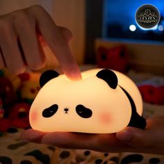 a person is holding a lamp that looks like a panda bear's face on it