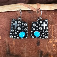 Four Directions Cross earrings with Turquoise by Akee Douglas, Navajo This design features a heavily oxidized background with varying sizes of sterling silver Navajo teardrops and crosses. The earrings showcase two pieces of blue turquoise. Materials: Turquoise, Sterling Silver Size: 3/4" square approximately Weight: 11 gr for both Signed: A Douglas Sterling   You might also like the complimentary pendant! Four Directions, Navajo Jewelry, Cross Earrings, Blue Turquoise, Turquoise Sterling Silver, Turquoise Blue, Two Pieces, Design Features, Jewelry Earrings Dangle