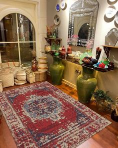 a room filled with lots of vases on top of a wooden floor next to a red rug