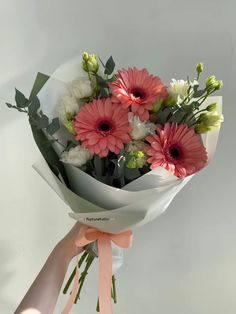 a bouquet of pink and white flowers in someone's hand