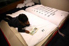 a woman laying on top of a bed next to two pillows with writing on them