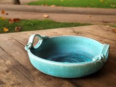 a blue bowl sitting on top of a wooden table next to a green grass field