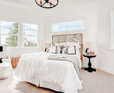 a bedroom with white walls and carpeted flooring has a chandelier hanging from the ceiling