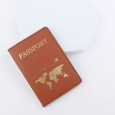 an orange passport case sitting on top of a white table next to a paper plane