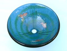 a blue glass bowl with gold fish in the water on it's rim and bottom