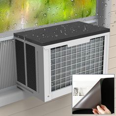 a window air conditioner with rain drops on it and a hand holding the side panel