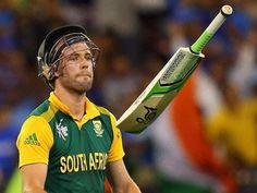 a man holding a cricket bat on top of his head in front of an audience