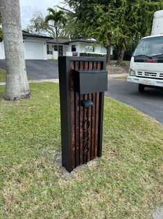 a trash can sitting in the grass next to a street with a truck behind it