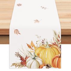 a table runner with pumpkins, leaves and acorns painted on the side